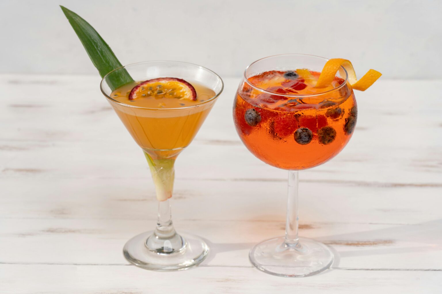 Two refreshing fruit cocktails in elegant glasses with garnishes.